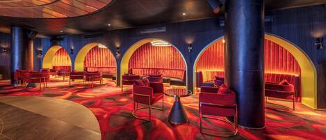 A spacious lobby with red and gold seating, large pillars, and a curved ceiling.