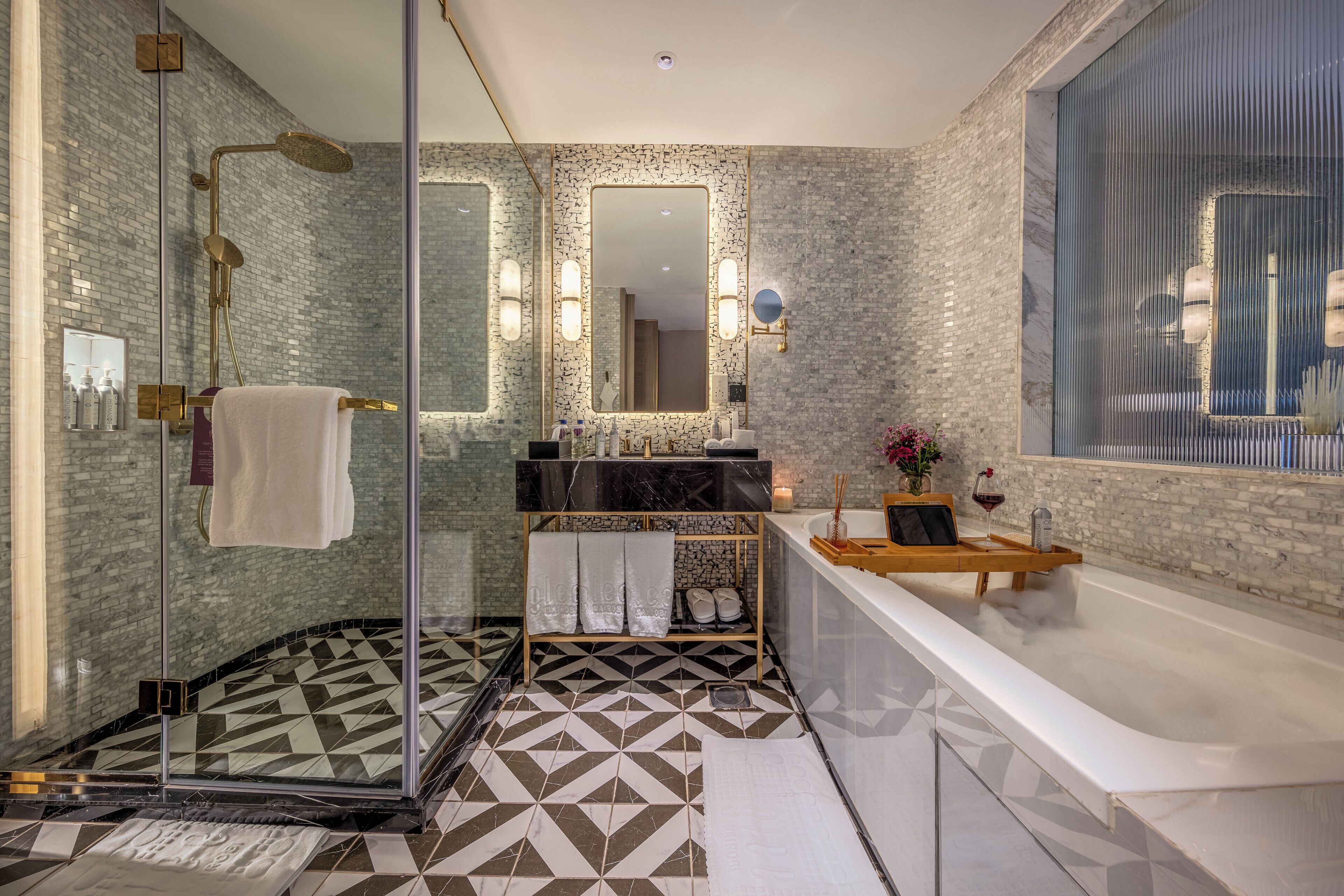 Un baño moderno con cabina de ducha de vidrio, un espejo grande, un lavamanos de mármol y una bañera.