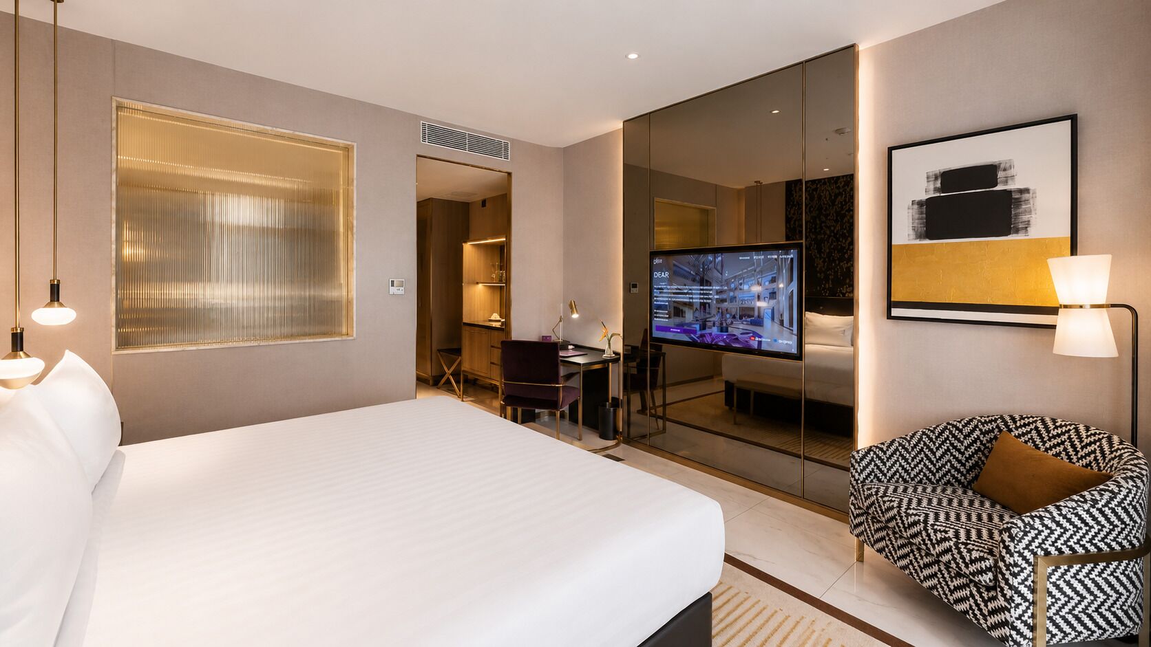 Une chambre d’hôtel avec un grand lit, un bureau avec une chaise, une télévision et un canapé.