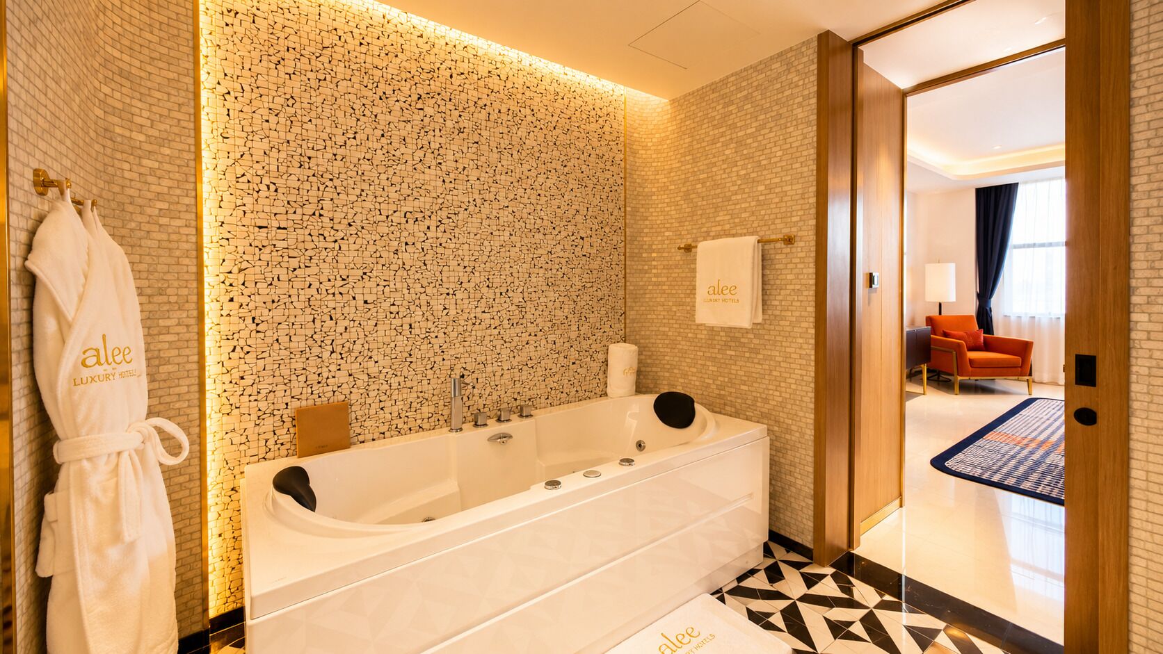 A modern bathroom with a large bathtub, a towel rack with a robe, and a patterned wall.