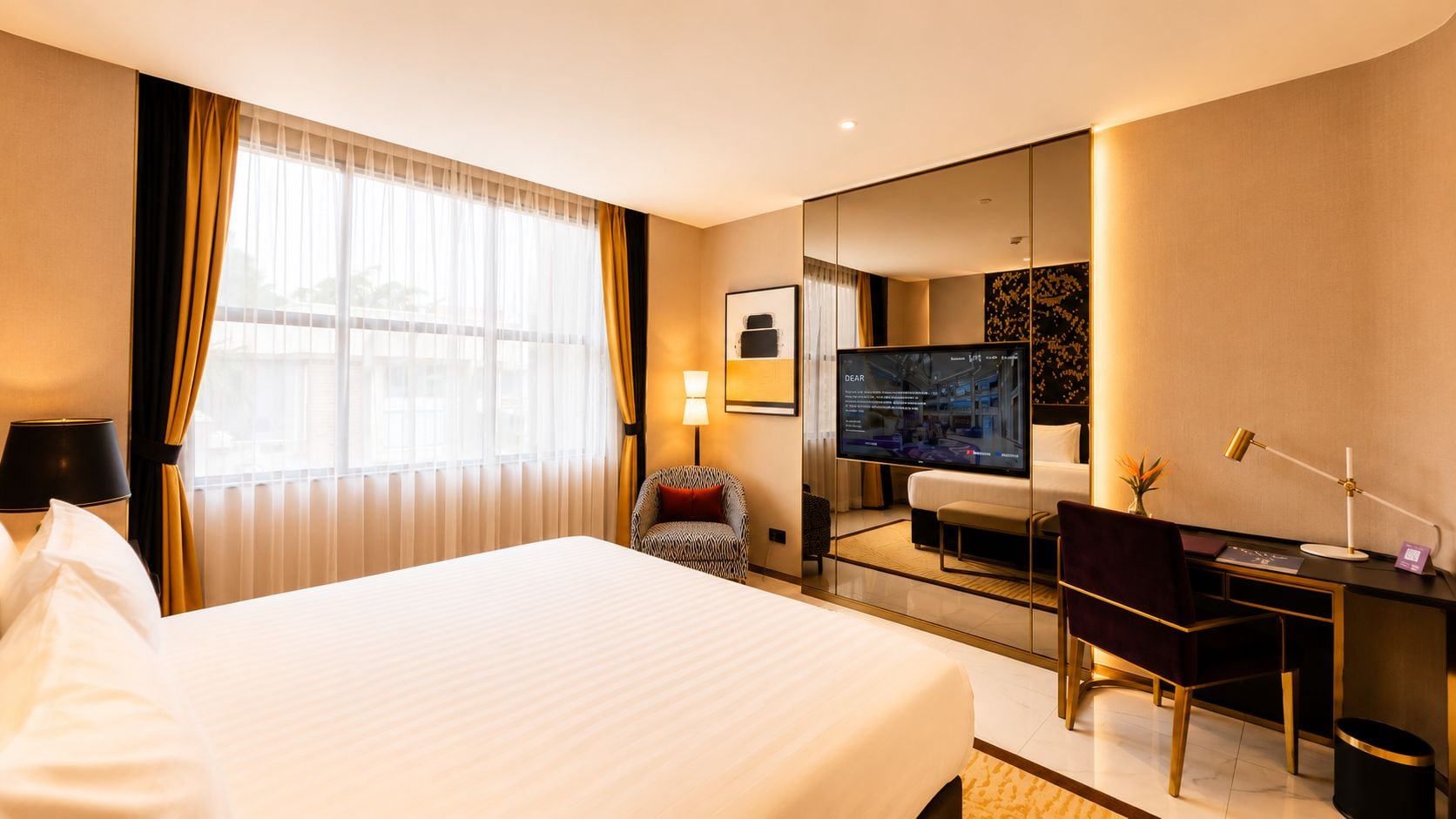 Habitación de hotel con una cama grande, un escritorio con computadora, televisión y espejo.
