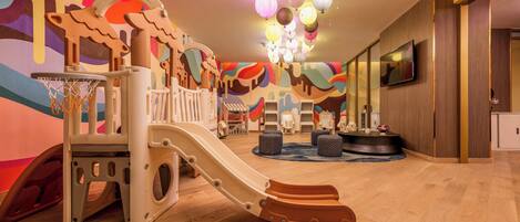 A play area with a slide, climbing structures, and a basketball hoop.