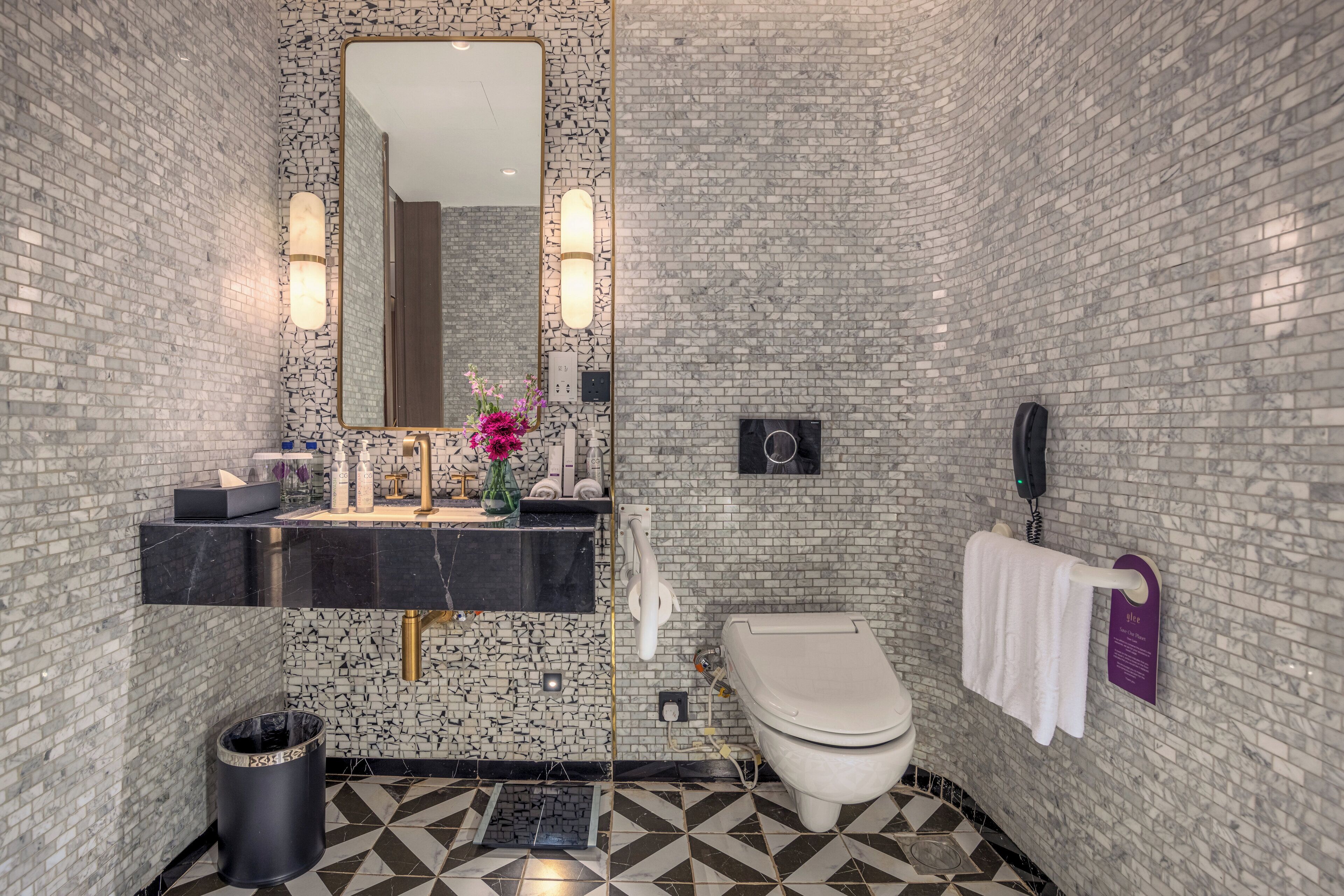 Un baño con tocador de mármol negro, inodoro blanco y cubo de basura.