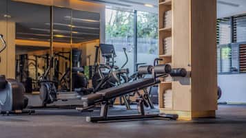 Une salle de sport équipée de matériel d’exercice, avec une colonne en bois et une vue sur l’extérieur.