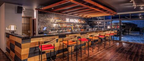 A bar area with a checkered counter, bar stools, and a 'BE AMAZING' sign.