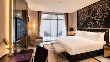 A hotel room with a large bed, a desk with a computer, a chair, a TV, and a view of the outdoors.