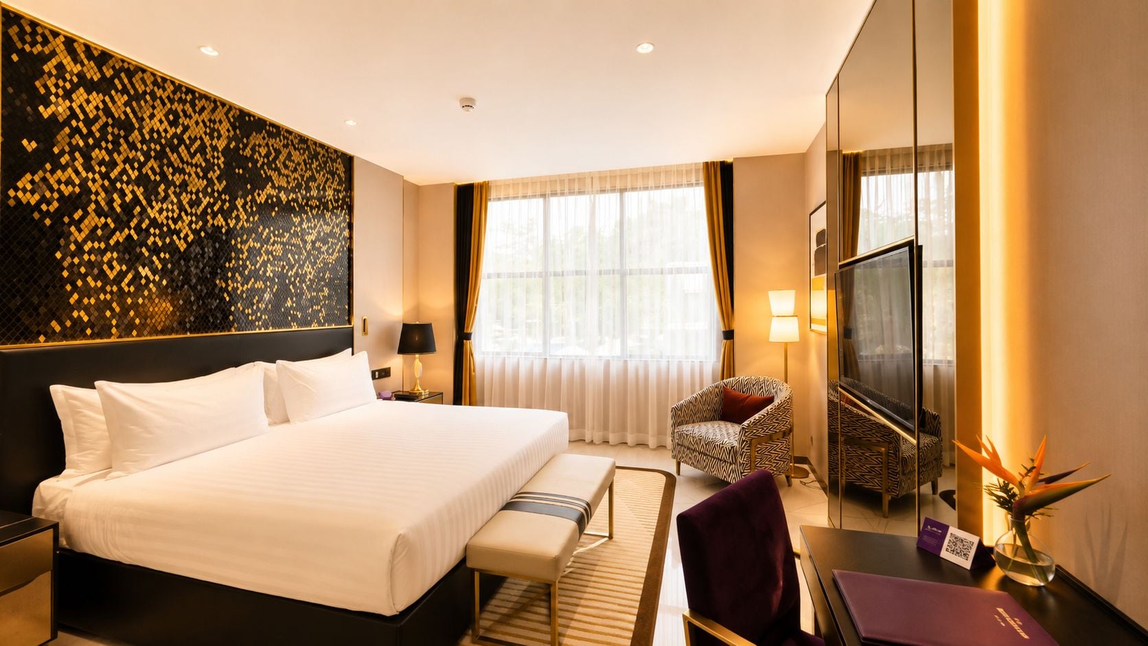 A hotel room with a large bed, a desk, a chair, a TV, and a window with curtains.