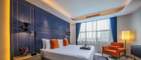 Una habitación de hotel moderna con una cama grande, una mesita de noche, una silla y un televisor.