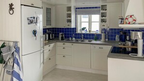 Een keuken met witte kastjes, een inbouwvaatwasser, een spoelbak en een koffiezetapparaat.