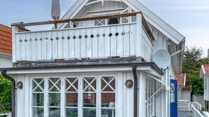Een wit gebouw met een balkon, meerdere ramen en een schotelantenne.