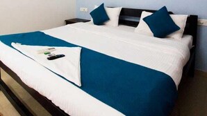 A neatly made bed with a white and blue bedspread, a black headboard, and two blue pillows. - White Seasons Resort And Spa (Malvan)