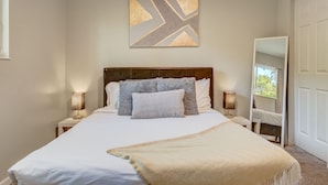A neatly made bed with a headboard, two bedside lamps, and a wall-mounted abstract art piece. - TJ Maxx (Colorado Springs)