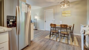 A modern kitchen with a stainless steel refrigerator, a water dispenser, and a dining area with a wooden table and chairs. - TJ Maxx (Colorado Springs)
