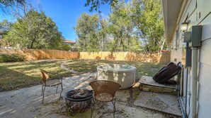 A backyard with a hot tub, two wicker chairs, a grill, and a wooden fence. - TJ Maxx (Colorado Springs)
