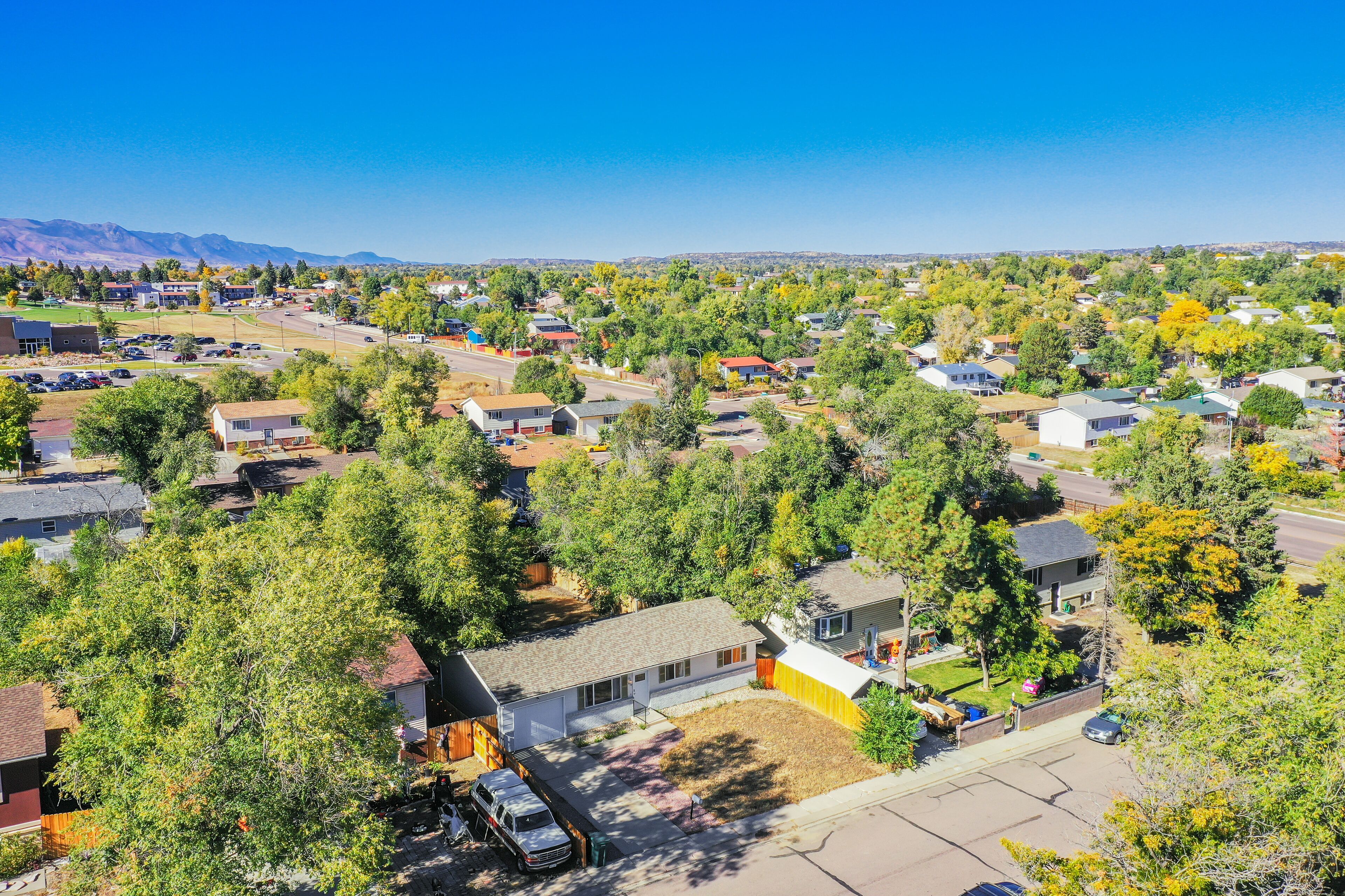 A residential area with houses, trees, and a clear sky.