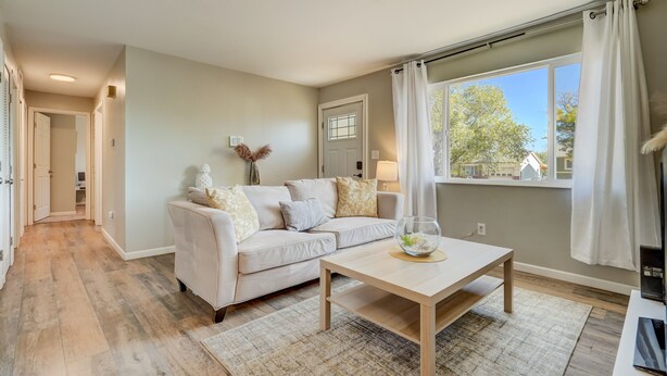 A modern living room with a sofa, coffee table, and a view of the outdoors through a large window. - TJ Maxx (Colorado Springs)