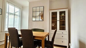 Un coin repas comprenant une table en bois et quatre chaises, un meuble avec des portes en verre et un miroir encadré accroché au mur.
