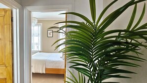 Une chambre avec un lit, une porte en bois et une grande plante verte.