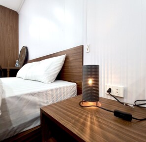 A neatly made bed with white linens, a wooden headboard, and a bedside table with a lamp. - Amelie Homestay (Hanoi)