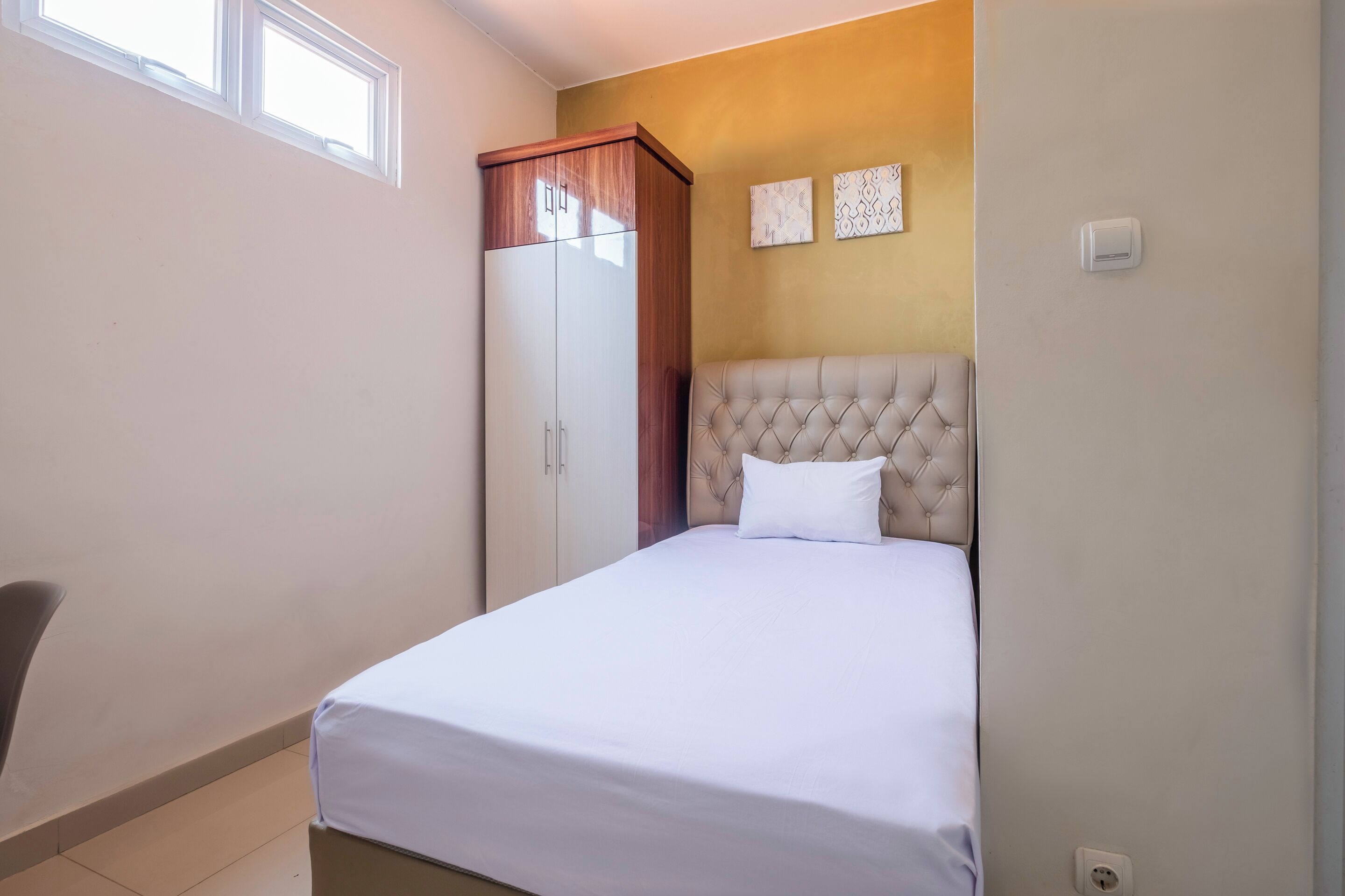 Quarto com cama, guarda-roupa e duas obras de arte penduradas na parede.