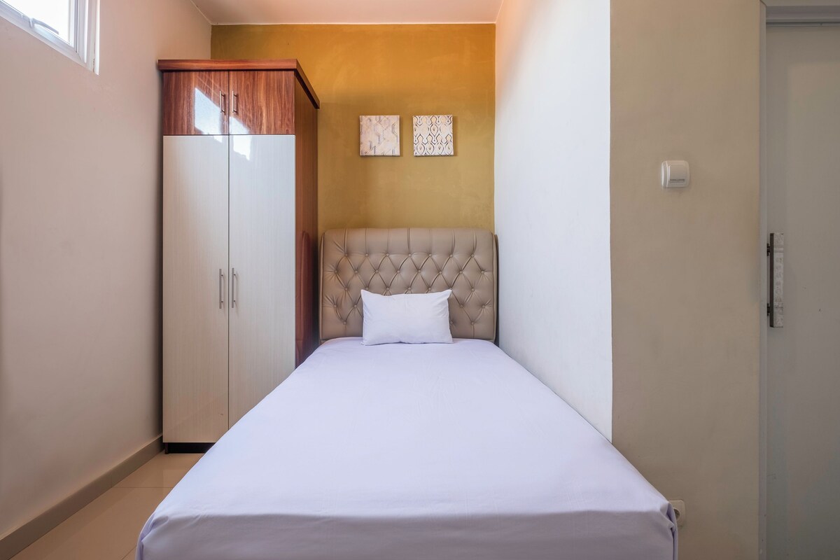 A bedroom with a bed, a wardrobe, and two wall-mounted artworks.