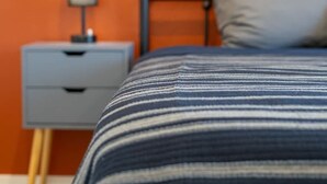 A bed with a striped blanket, a nightstand with a lamp, and a gray drawer unit. - 5BR/3BA Mountain Retreat: Fun in Flagstaff (Flagstaff)