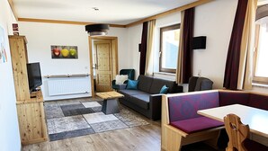 Una sala de estar acogedora con un sofá, una mesa de comedor y un televisor.