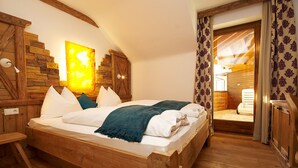 Una cama de madera en una habitación con pared de piedra y techo de madera.