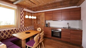 Una cocina moderna con armarios de madera, horno empotrado y comedor con banco y sillas.