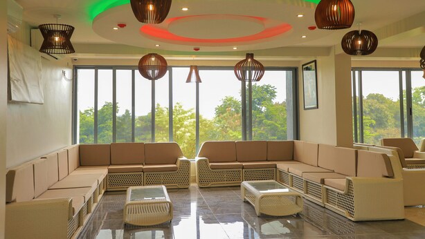 A spacious lounge with a large sectional sofa, a coffee table, and wicker chairs. - Le tsuba Grand Hotel (Arua)