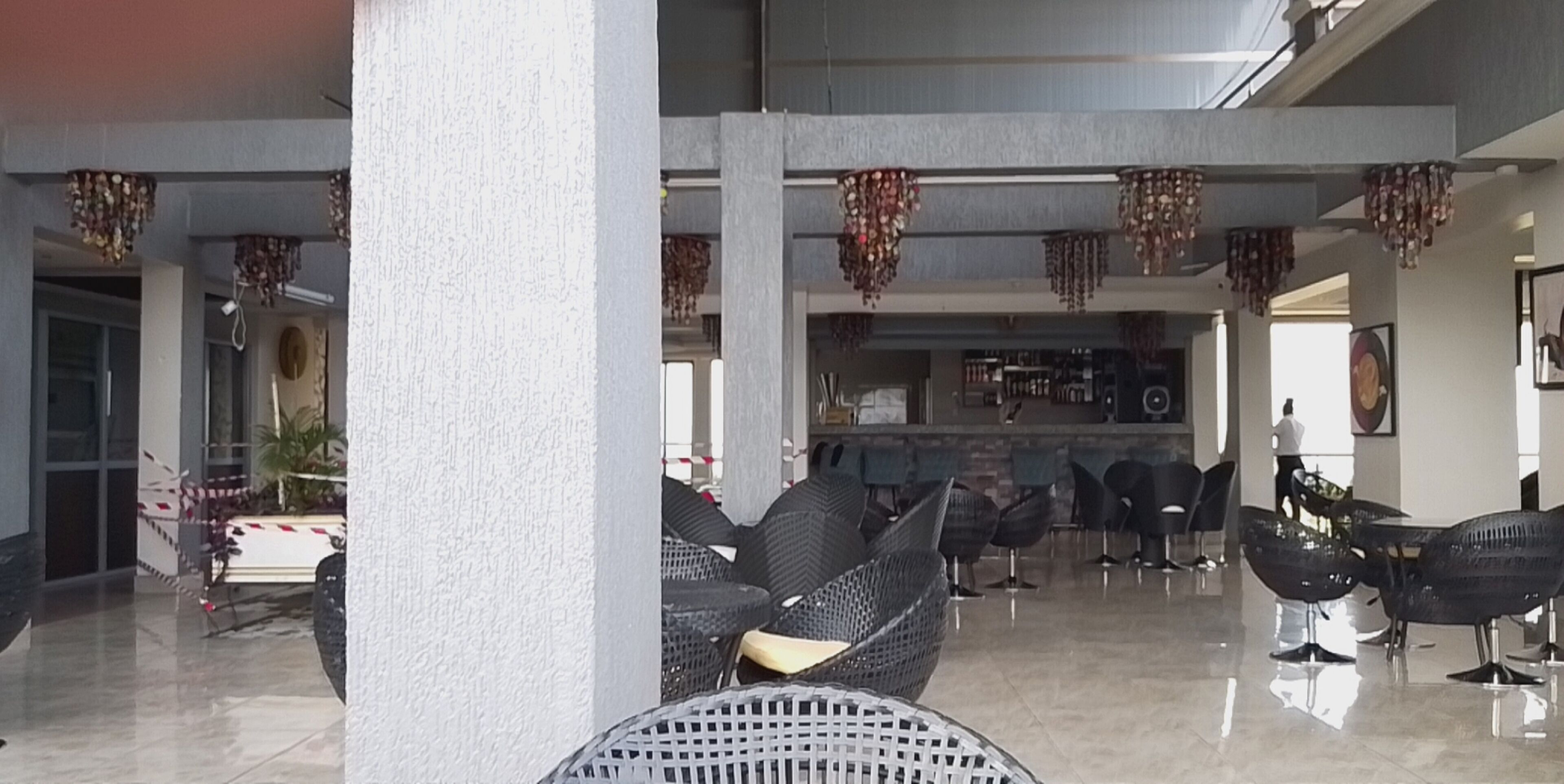 Un vestíbulo espacioso con muebles de mimbre modernos, una zona de bar y elementos decorativos colgantes.