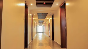 A long, narrow hotel corridor with doors on both sides, recessed lighting, and a patterned ceiling. - Le tsuba Grand Hotel (Arua)