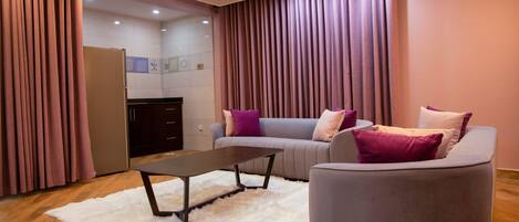 A modern living room with a sofa, a coffee table, and a kitchen area in the background.