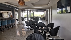 A modern interior with a bar area, seating with high backs, and a view to the outdoors. - Le tsuba Grand Hotel (Arua)