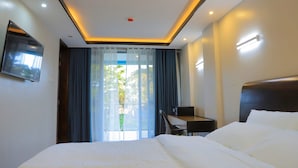 A modern hotel room with a large bed, a desk, and a TV mounted on the wall. - Le tsuba Grand Hotel (Arua)