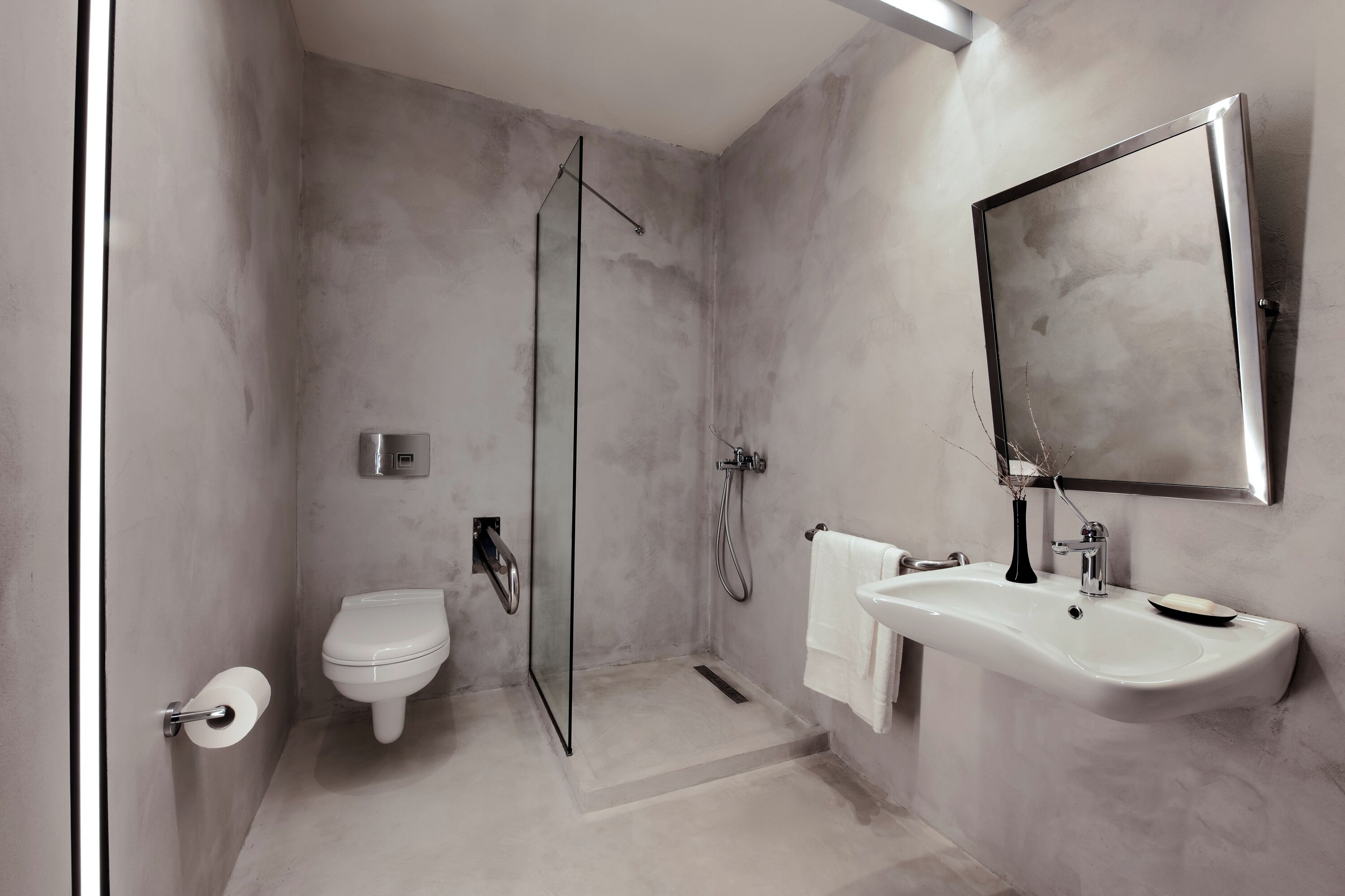A modern bathroom with a glass-enclosed shower, a white toilet, and a sink with a mirror.