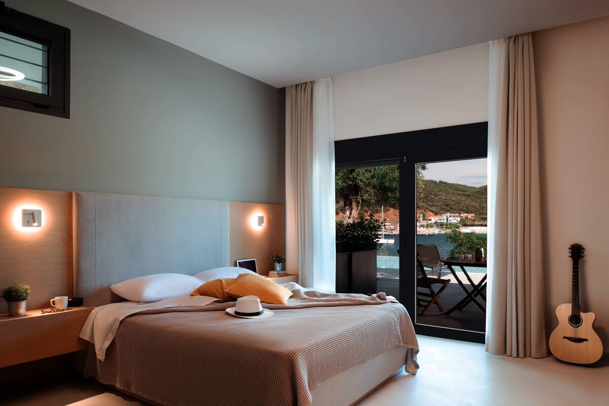 A modern hotel room with a large bed, a guitar, and a view of a pool and landscape.