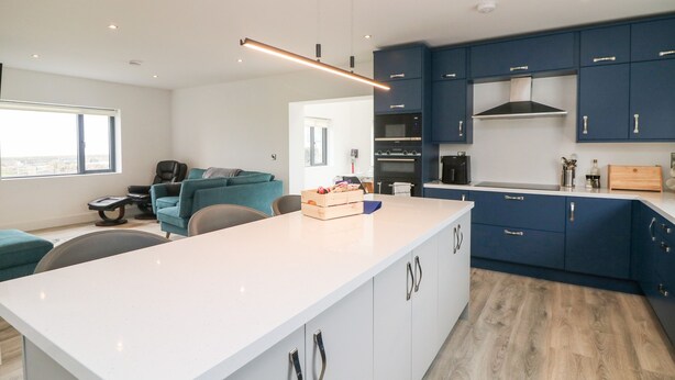 A modern kitchen with blue cabinets, a white countertop, and a built-in oven. - Old Field House (Templetown)