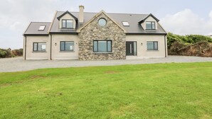 A two-story house with a stone facade, a central circular window, and a sloped roof. - Old Field House (Templetown)
