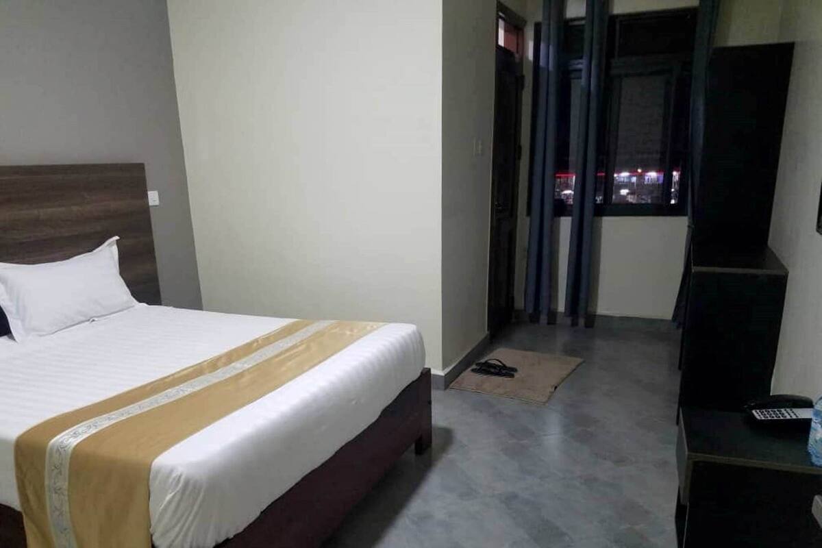 Habitación de hotel con cama, escritorio y vista a la ciudad de noche.