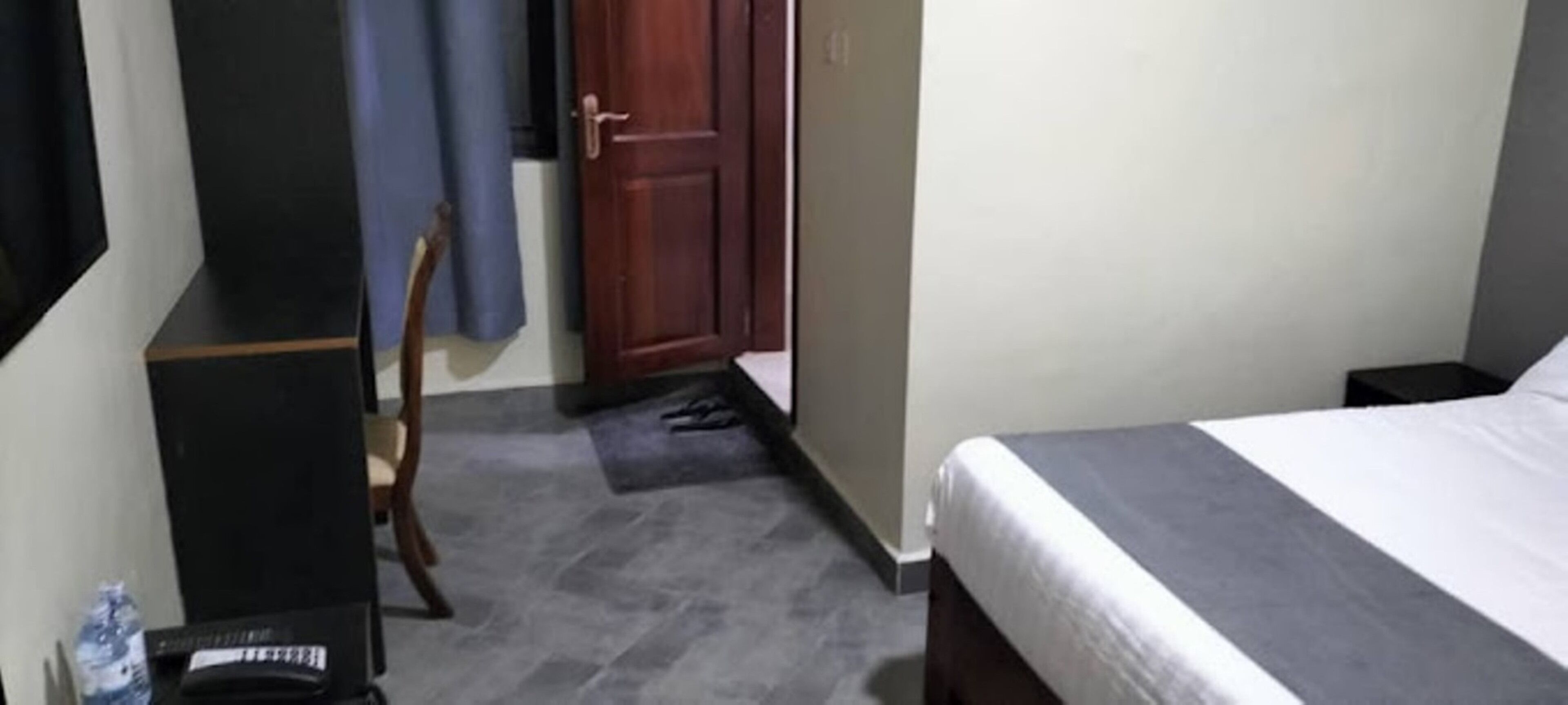 Un dormitorio con una cama, una silla, un armario de madera y una puerta.
