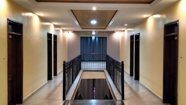 Un pasillo con una escalera central, puertas a ambos lados y una lámpara en el techo.