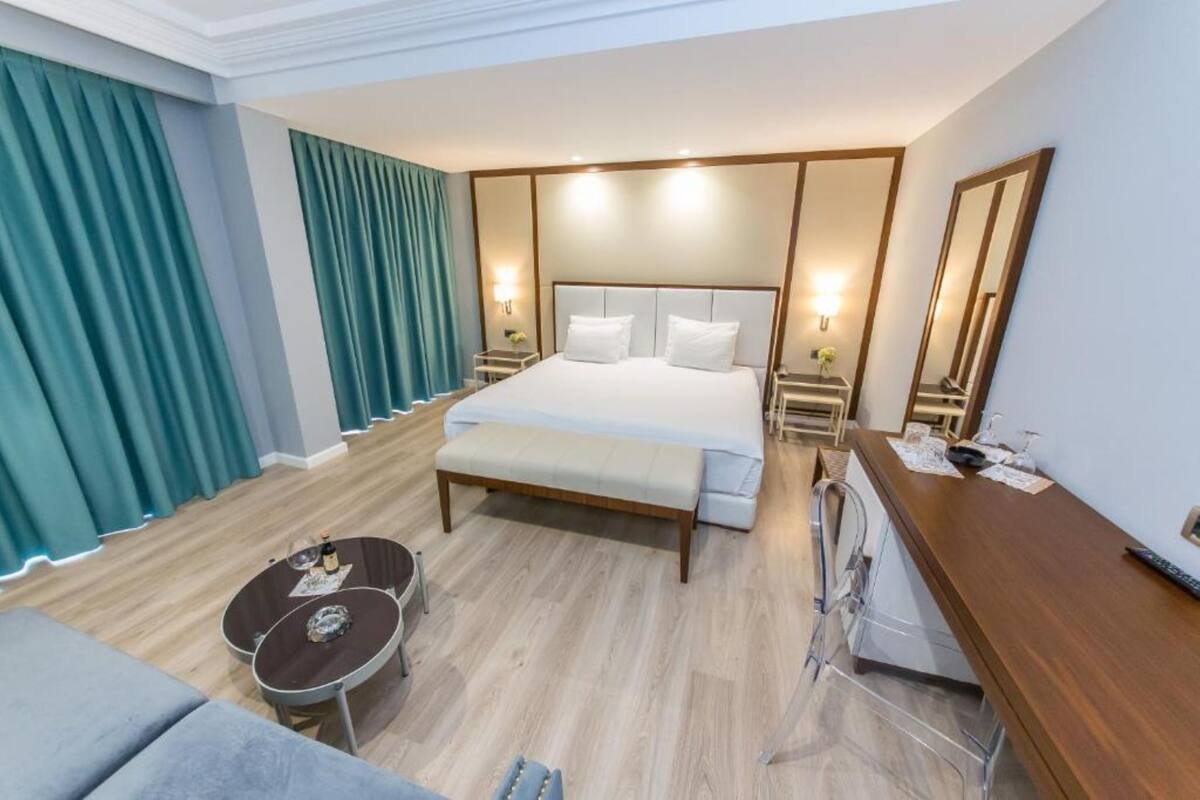 Una habitación de hotel con una cama grande, un escritorio, una silla, una mesita y un sofá.