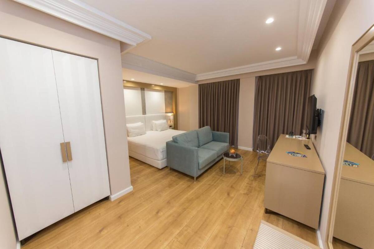 Una habitación de hotel con una cama, un sofá azul, un escritorio y un armario.