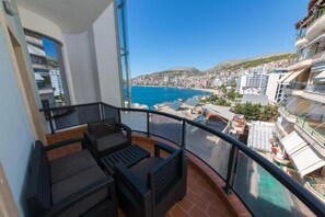 A balcony with outdoor furniture, a clear view of a coastal town, and a hillside in the background. - Hotel Brilant (Sarandë)