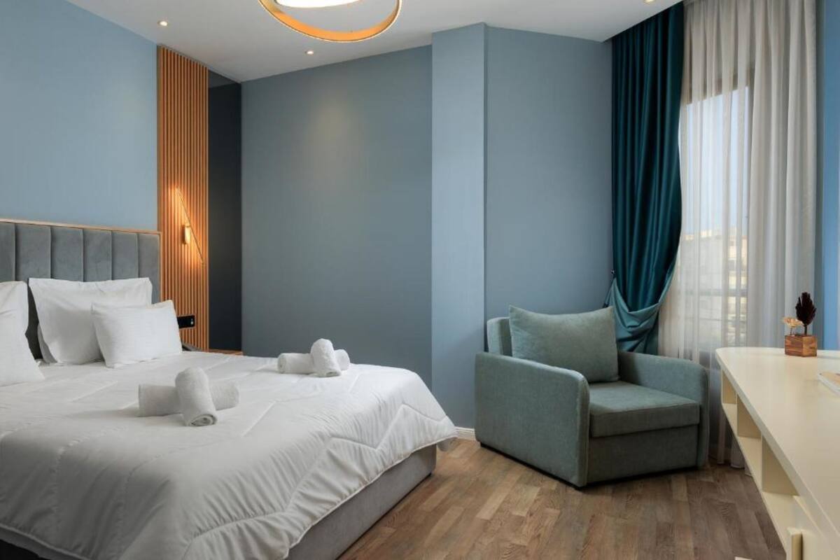 Una habitación de hotel moderna con una cama grande, una zona de estar y un escritorio.
