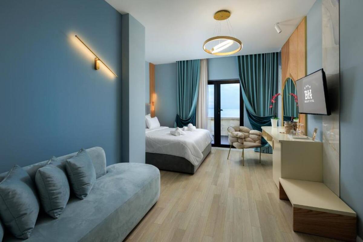 Una habitación de hotel moderna con cama, sofá, escritorio y televisión.