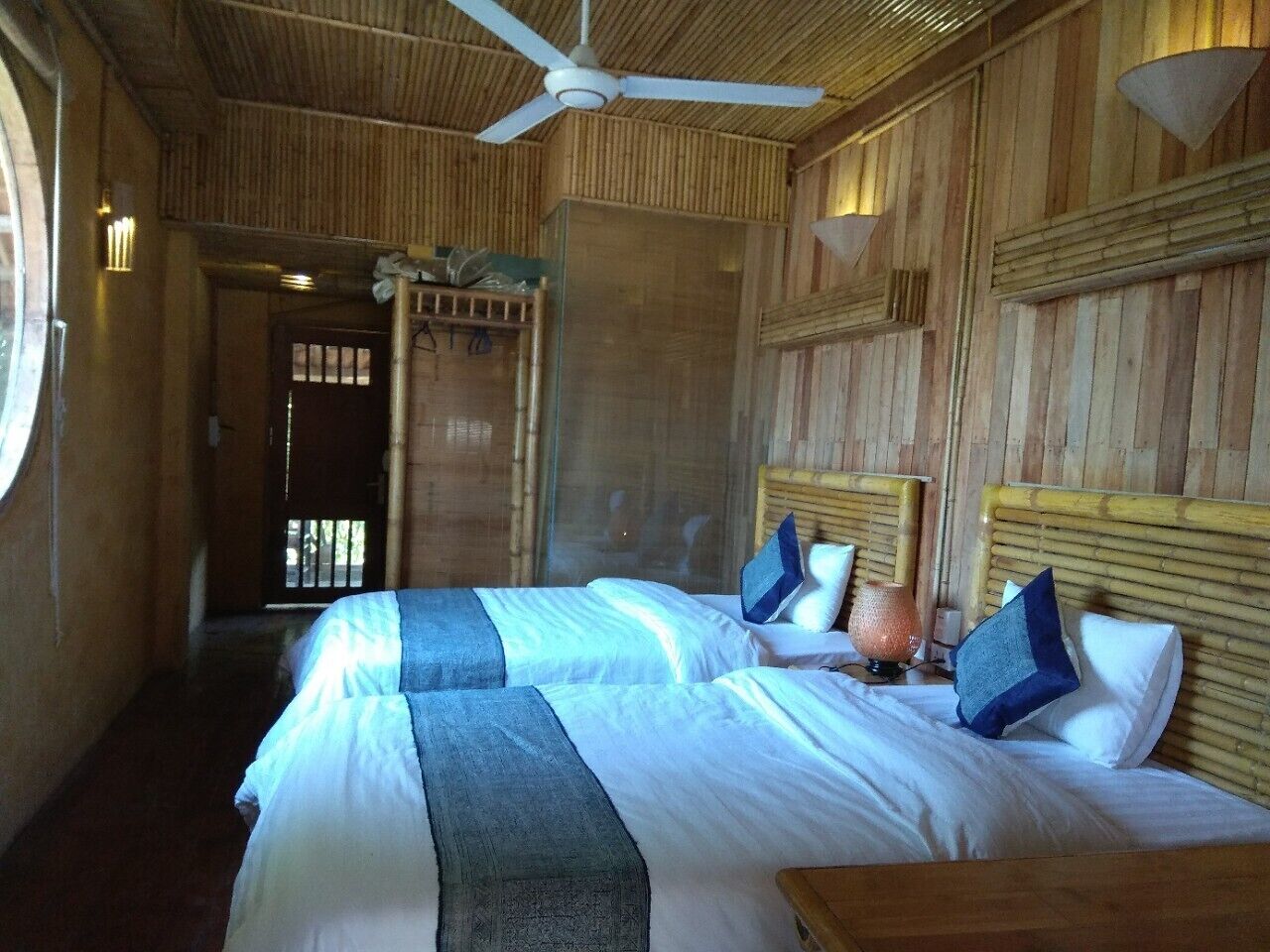 Una habitación con dos camas, un ventilador de techo y una ventana.