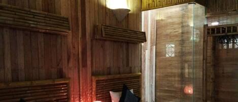 Una habitación con dos camas, paredes de madera, un ventilador de techo y una mesita de noche con lámpara.