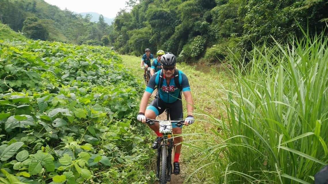 A cyclist on a trail surrounded by lush greenery.